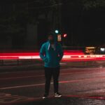 Man standing on empty city road at night