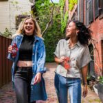 woman in blue denim jacket standing beside woman in white shirt